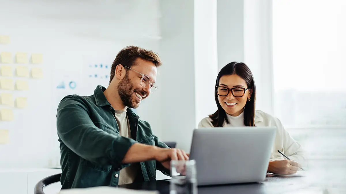 Happy man and woman looking at laptop in lab environment